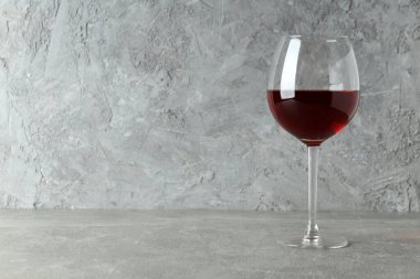 Gri dokulu masada bir kadeh kırmızı şarap.