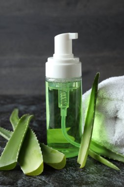 Aloe yaprakları, kozmetik ve havlu siyah dumanlı masada.