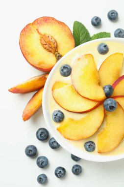 Beyaz arka planda şeftalili yoğurt ve malzemeler