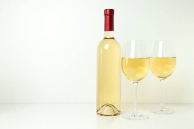 Şişe ve bardaklar beyaz masada.