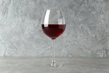 Gri dokulu masada bir kadeh kırmızı şarap.