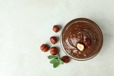 Çikolata ezmeli kase, fındık ve naneli beyaz desenli arka plan.