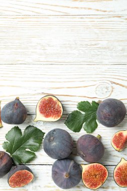 Beyaz ahşap arka planda yaprakları olan incir