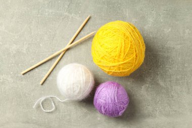 Açık gri arka planda iplik topları ve örgü iğneleri