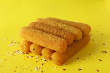 Sarı arka planda peynir çubukları ve baharatlar