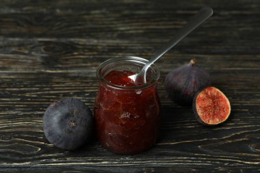 İncir reçeli, kaşıklı kavanoz ve ahşap arka planda malzemeler.