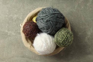 Açık gri masada yün yumakları olan hasır sepet.