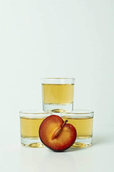 Plum vodka shots and ingredients on white background