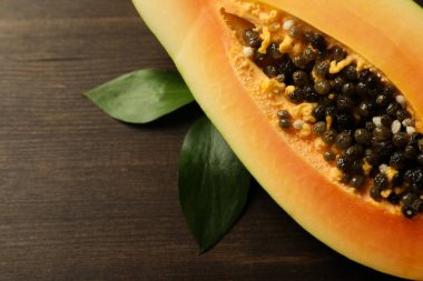 Ahşap arka planda yaprakları olan papayanın yarısı.