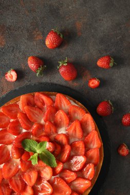 Koyu dokulu masada çilekli tart tepsisi.