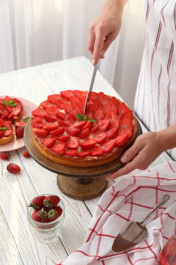 Önlüklü kadın çilekli turtayı kesti..