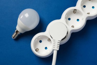 Mavi arkaplanda enerji tasarrufu ampulü ve güç şeridi.