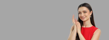 Tarafsız gri arka planda gülümseyen ve ürünü sunan kadın