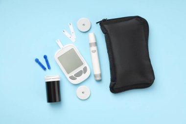 Mavi arka planda düzenlenmiş glikoz ölçer ve diyabet malzemeleri