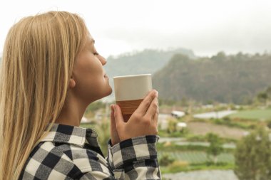 Güzel manzaranın tadını çıkarırken ılık bir içkinin tadını çıkarıyorum.