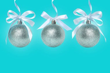 Mavi arka planda beyaz fiyonklu üç gümüş süs.