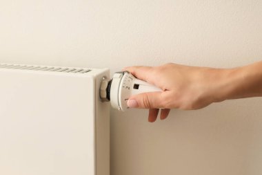 Isınmak için radyatörün termostatını çeviriyor.