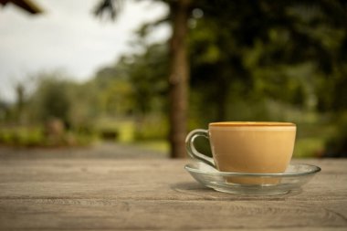 Arkasında yeşillik olan bir masada kahve.