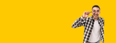 Genç adam sevinçle gülümserken gözlüklerini ayarlıyor.