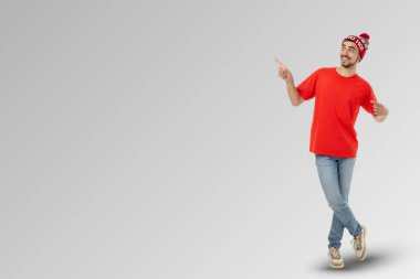 Kırmızı tişörtlü genç adam ve şenlik şapkası yan tarafı işaret ediyor.