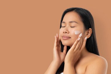 Bir kadın spa gününün tadını çıkarırken yüzüne krem sürüyor.