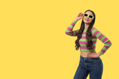 Renkli kıyafetler giyerken manken durur ve gülümser.