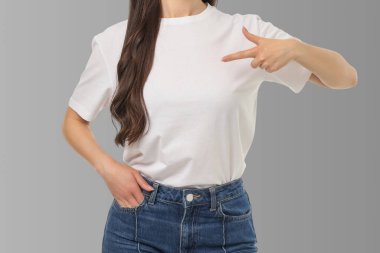 Kadın stüdyo arkaplanındaki tişörtteki boşluğa işaret ediyor