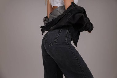 Model siyah kot pantolon ve katmanlı dış giysi ile poz verir.