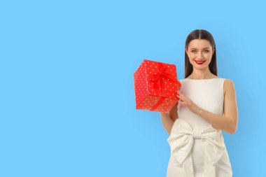 Beyaz elbiseli bir kadın kırmızı hediye kutusunu sunuyor.
