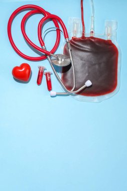 Stetoskop ve mavi yüzeyde kalp şeklinde kan torbası.