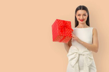 Woman presenting a red gift box with white polka dots
