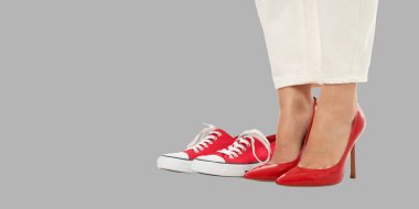 Bir kadın iki çeşit ayakkabı, spor ayakkabı ve topuklu ayakkabı gösterir.