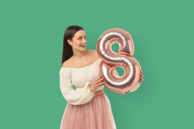 8 şeklinde büyük bir balonla gülümseyen genç bir kadın.
