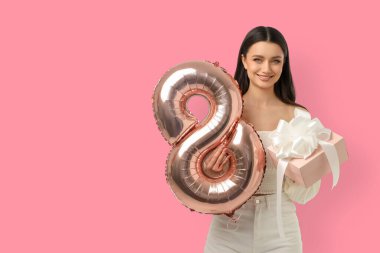 Genç bir kadın elinde 8 Mart için bir hediye ve balon tutuyor.