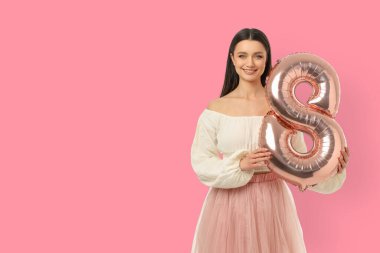 Genç bir kadın elinde büyük bir balon tutarken gülümsüyor.