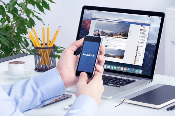 Facebook app on the Apple iPhone display and Apple Macbook Pro — Stock Photo, Image