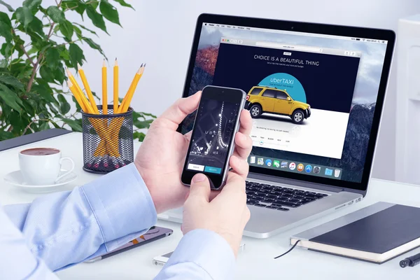 Uber app iphone üzerinde görüntülemek adam el ve Uber Web sitesinde Macbook Pro ekran