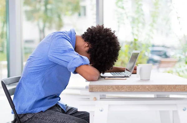 Hombre afro cansado con portátil — Foto de Stock