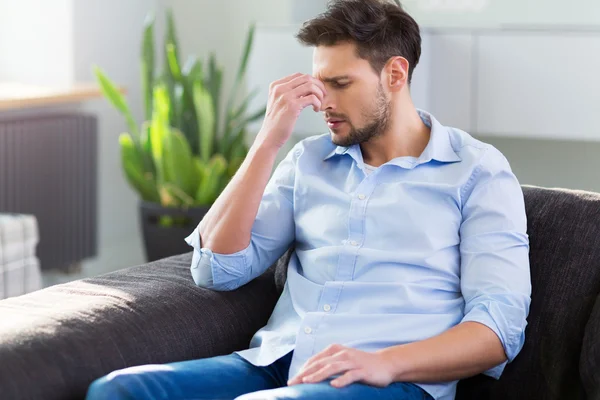 Hombre en sofá teniendo dolor de cabeza — Foto de Stock