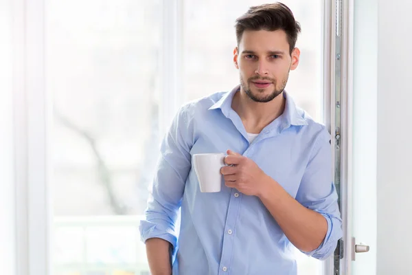 Человек пьет чашку кофе у окна — стоковое фото