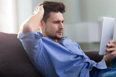 Dijital tablet ile kanepede oturan adam