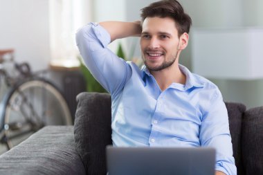 dizüstü bilgisayar ile kanepede oturan adam