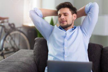 dizüstü bilgisayar ile kanepede oturan adam