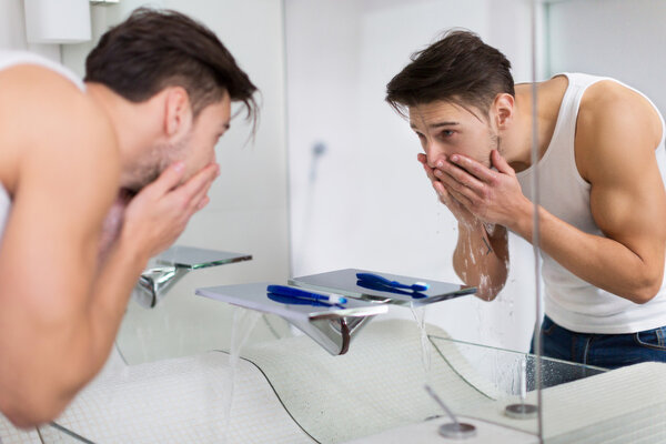 Man washing face in bathroom