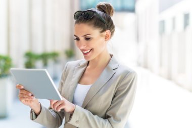 Dijital tablet kullanan çekici genç bir kadın.