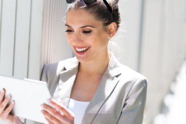 Dijital tablet kullanan çekici genç bir kadın.