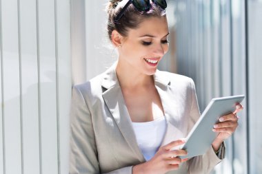 Dijital tablet kullanan çekici genç bir kadın.