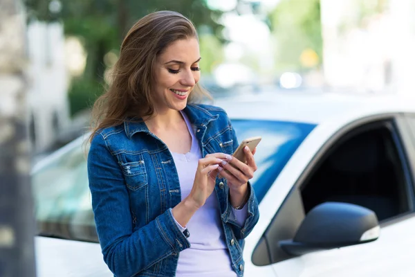 Kobieta przy użyciu telefonu komórkowego w pobliżu samochodu — Zdjęcie stockowe