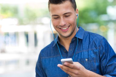 Cep telefonundan müzik dinleyen adam.