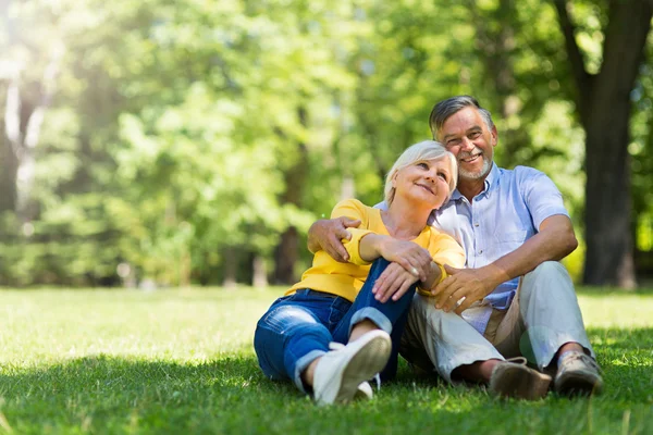 Seniorenpaar sitzt auf Gras — Stockfoto